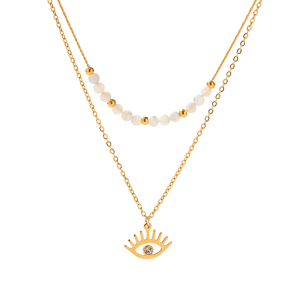 A gold-colored necklace with white beads and a decorative eye-shaped pendant.