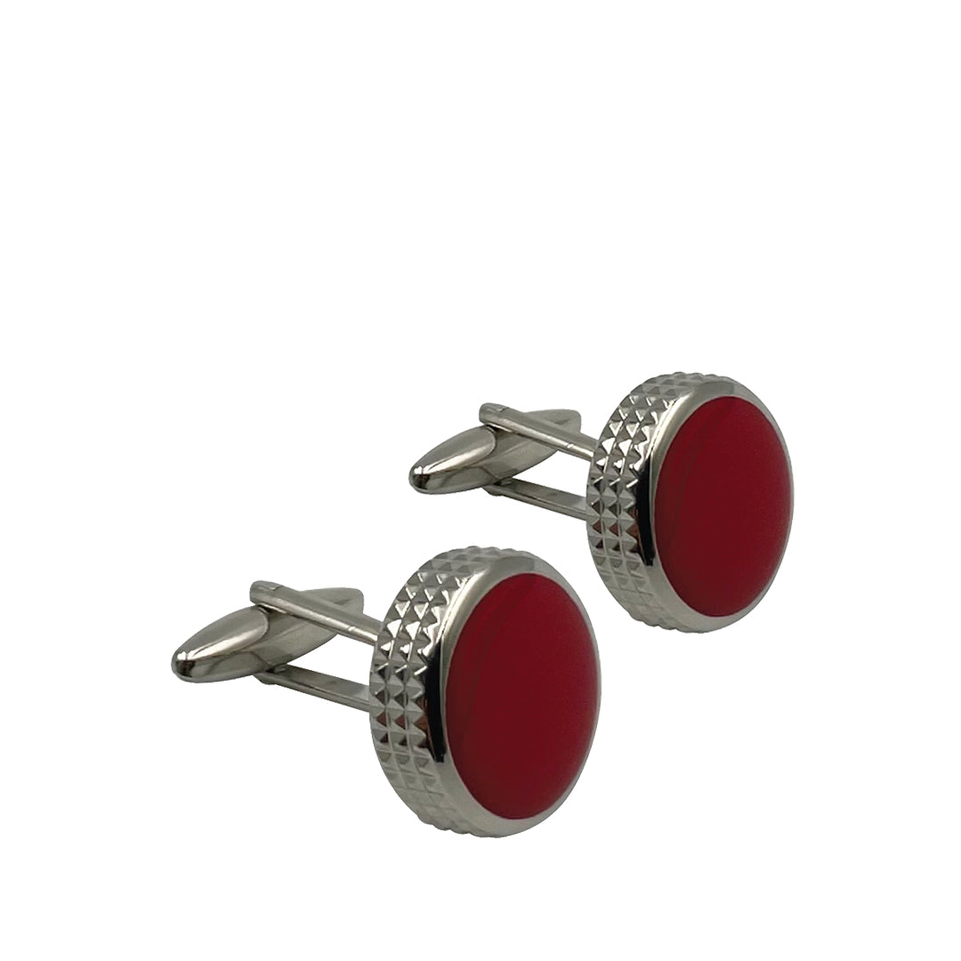 A pair of silver and red enamel cufflinks with a round shape and textured edge design.